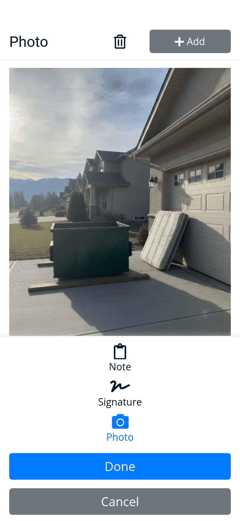 The driver app’s photo of the drop: the 10-yard dumpster on two boards in the driveway, next to the garage